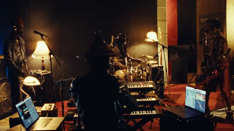 Dakar Session : le collectif en studio, claviers, batterie et lampes allumées, un musicien de dos coiffé d'un chapeau conique